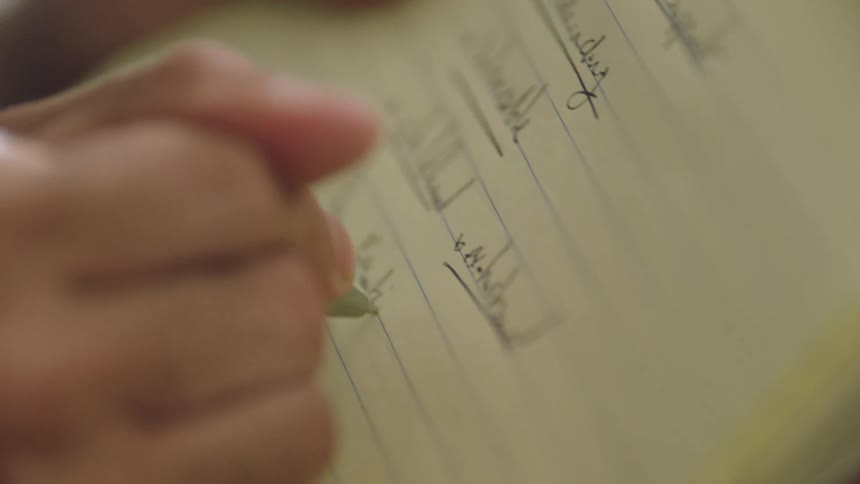 A person writing notes with a pen on a notebook