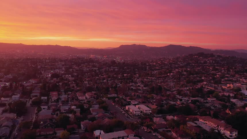 Town under a red and orange sky with a silhouette of mountains on the horizon