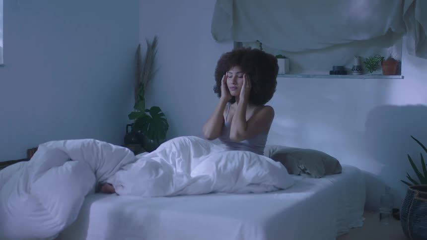 Young woman with an afro waking up and getting out of the bed