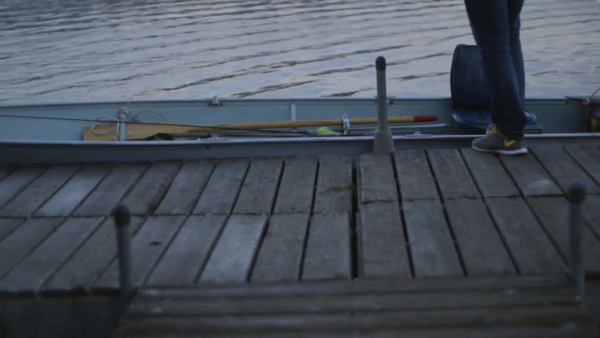 A person stands on a dock by a boat