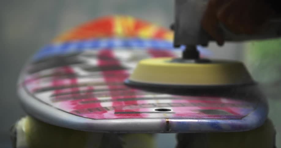 A person is polishing a surfboard with a pad