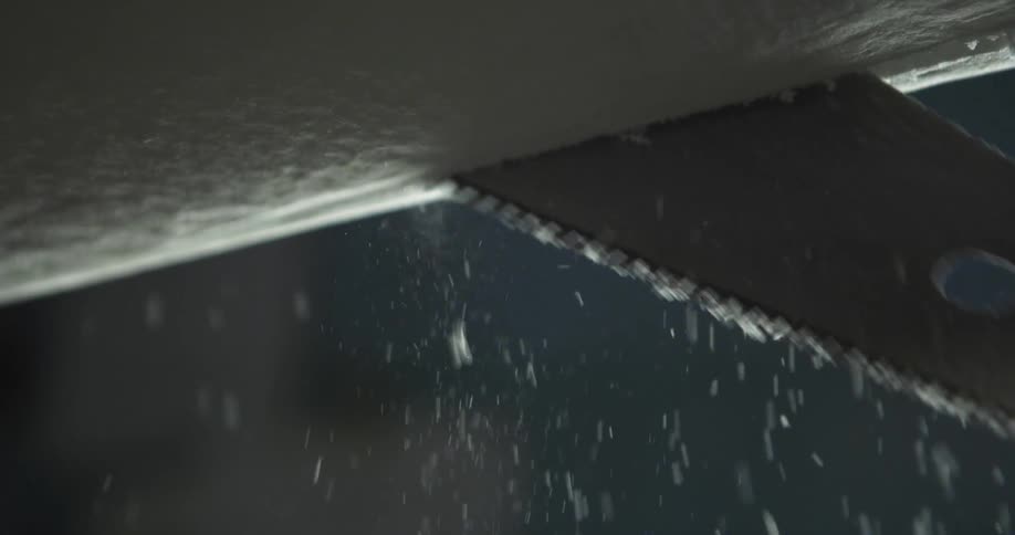 A saw cutting through the core of a surfboard