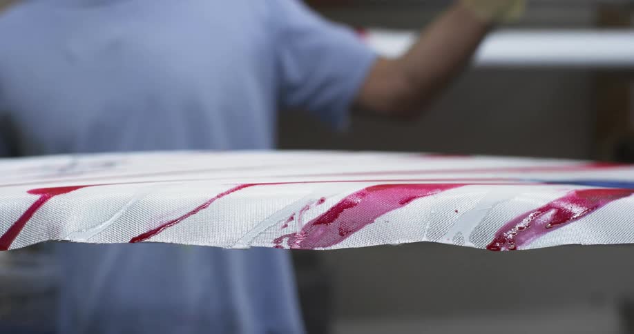 A warehouse worker stands behind a ledge covered with plastic that is painted with fresh red stripes
