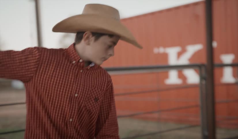 Youth moves hay closer to corral fence