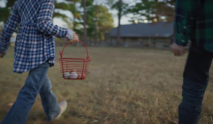 A girl proudly shows her dad the eggs she collected from their chicken coop as they walk back to their house