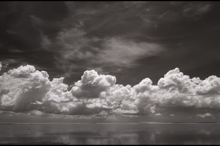 White clouds roll over the water surface which reflects the sky