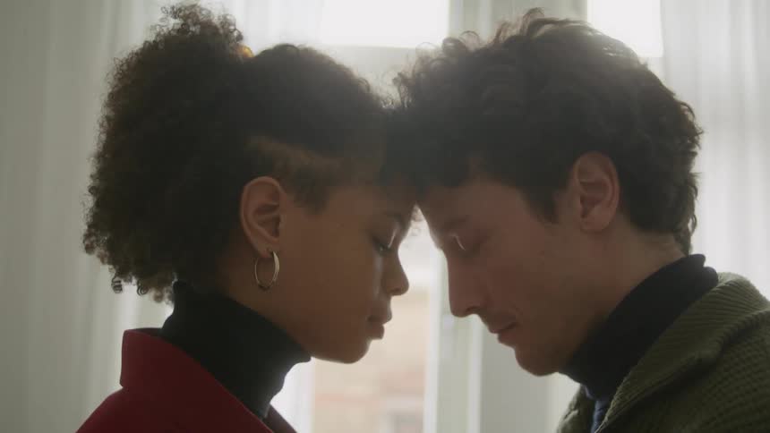 Young couple touching foreheads in front of a window