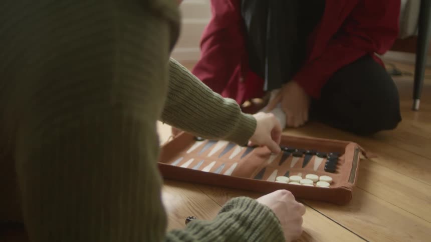 A man and a woman on the floor playing a board game with dice