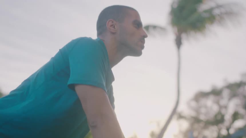 Man with turquoise t shirt does push ups in the park
