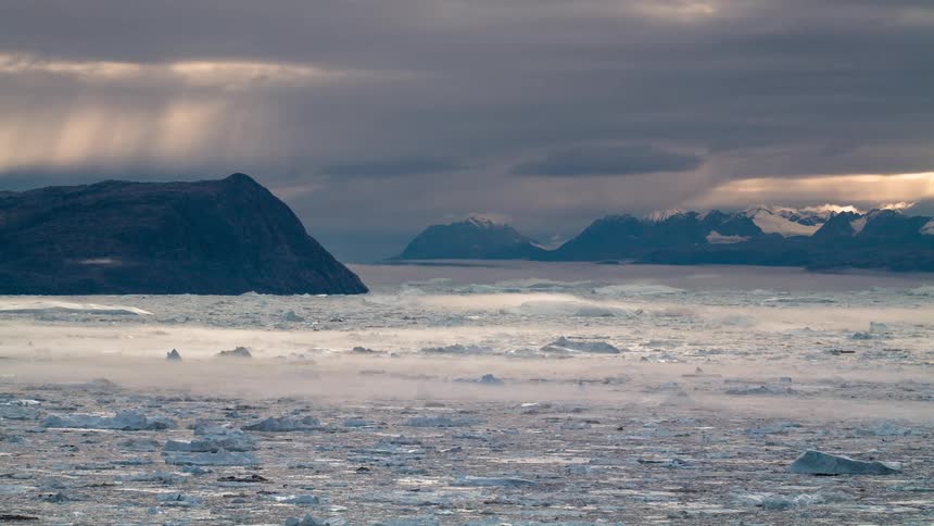 Time lapse of clouds running over the mountain range in the frozen arctic ocean