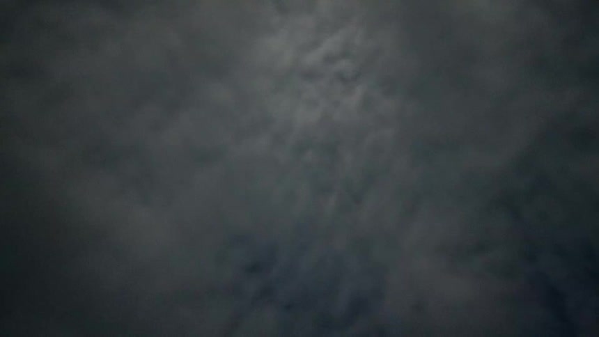 Clouds move by in a star filled sky and the northern lights shine green
