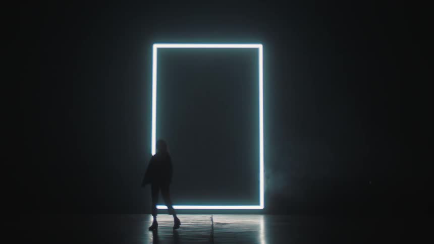 A silhouette of a woman paces back and forth in front of a screen flashing the words fifty percent off in a dark room