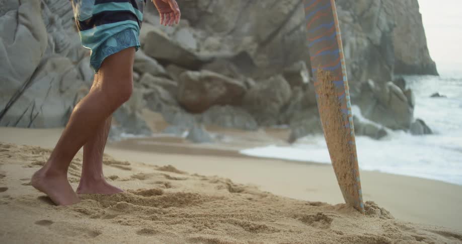Kicking sand onto a skimboard near shoreline at the beach