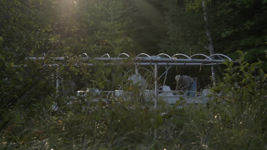 A man is bent over behind a fence
