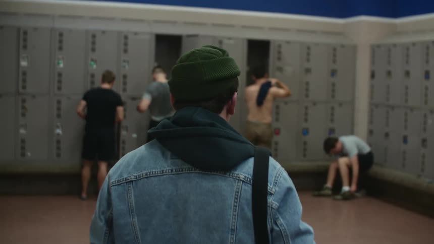 A person entering a locker room where young people are changing clothes