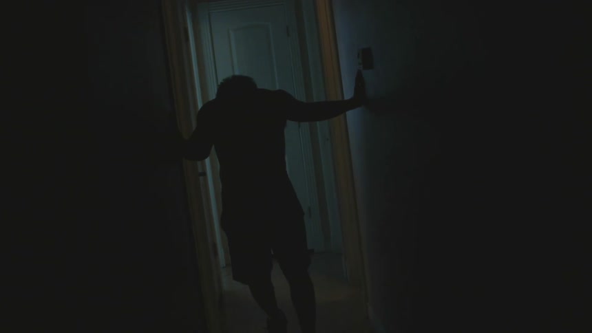 A man stumbles down the dark hall