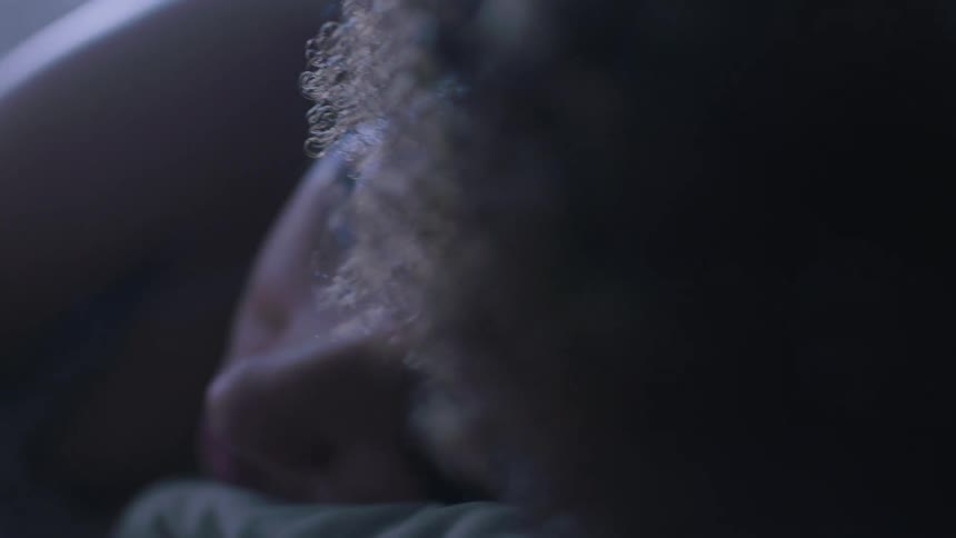 A woman sleeping in a bedroom on a bed with a pillow