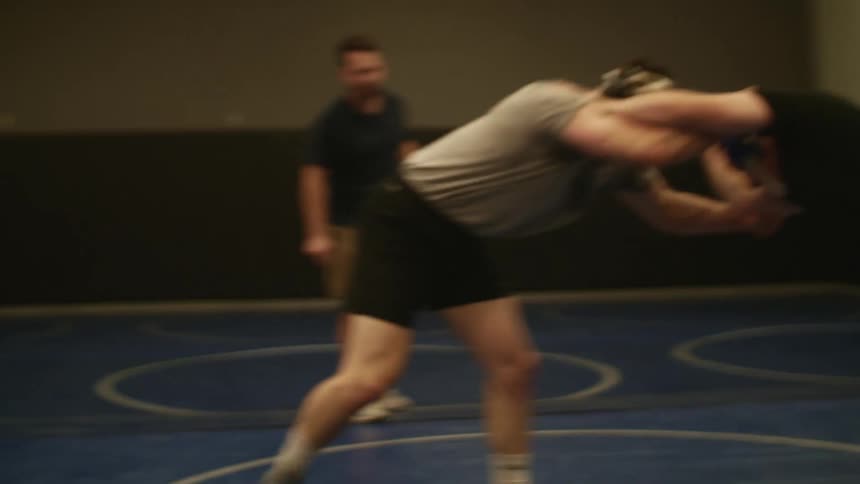 Two men in a gym practicing wrestling