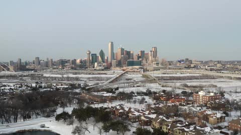 Skyline of a city at daytime with connecting highways and a neighborhood with houses and apartment buildings with snow on the ground