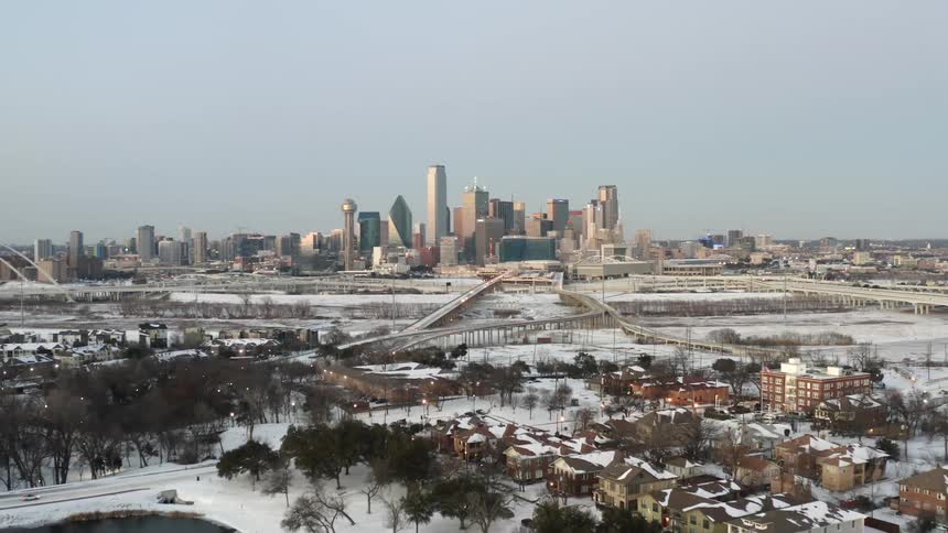 Skyline of a city at daytime with connecting highways and a neighborhood with houses and apartment buildings with snow on the ground