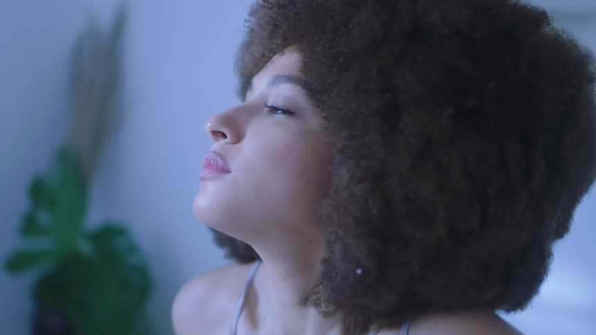 Young woman with an afro waking up in bed at home
