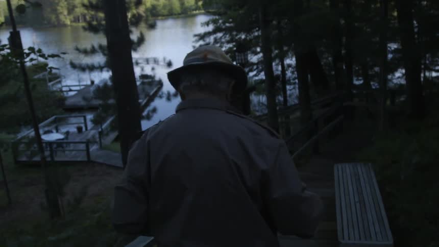 A man wearing a hat walks down wooden steps