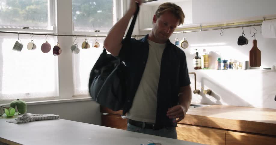 A man that is picking up a bag and walking out the room