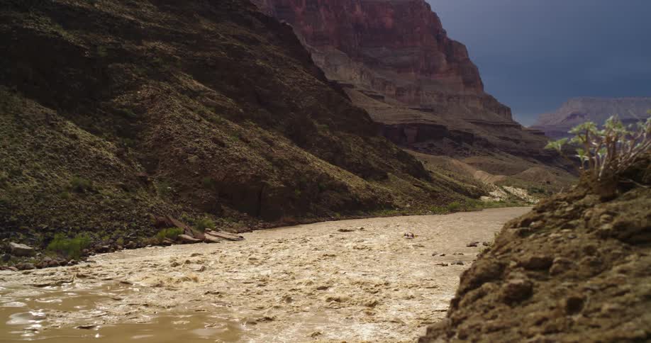 The muddy whitewater rapids of the Grand Canyon of the Colorado River just before a monsoon season thunderstorm drops rain on the river valley in August