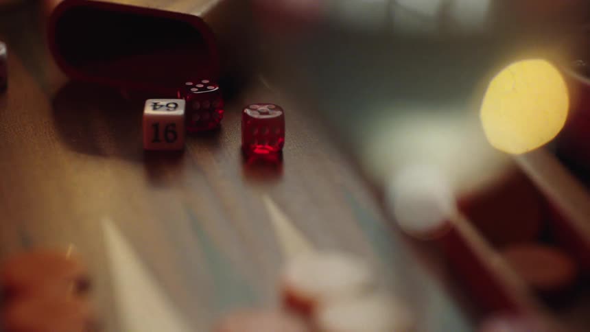 A wooden backgammon board with red and white dice and orange game pieces