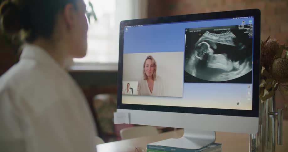 A doctor speaks with a patient on a video call from her laptop as they look at an ultrasound