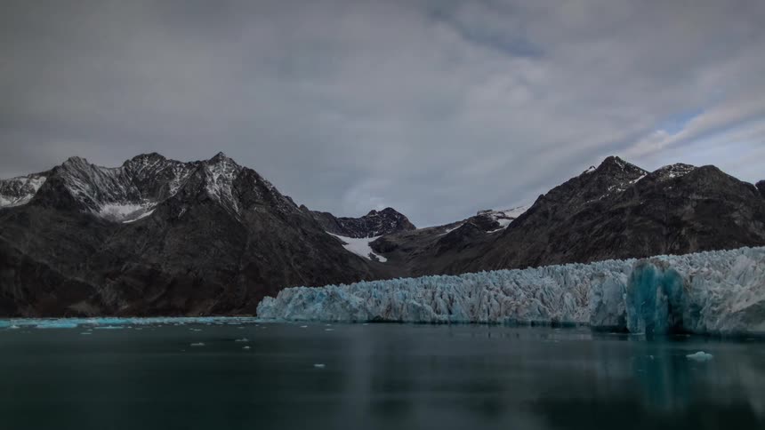 Time lapse of clouds passing over the snow covered mountain peaks near a glacier