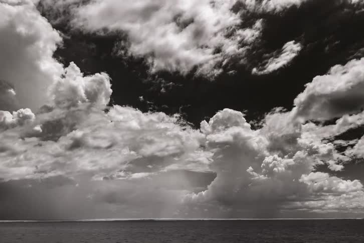 A body of water with rippling water and lightning with the sky and clouds in the background