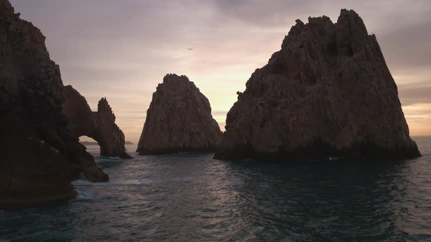 Rock arch and rock formations in the water under a cloudy sky