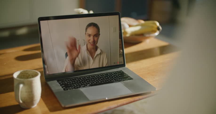 A laptop screen goes black as a woman waves goodbye during a video call at home