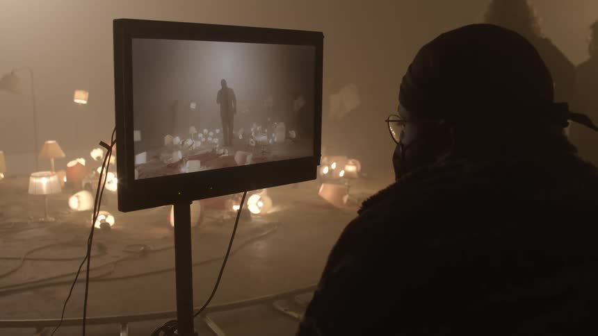 Filmmaker looking at the a screen while filming a scene inside a smoky room