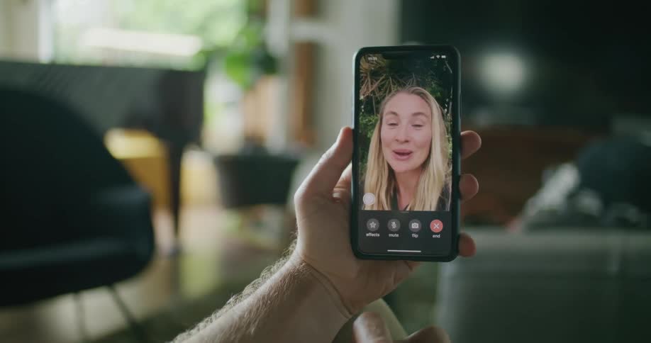 A man and woman speak to one another through video chat on their smartphones before waving goodbye to one another