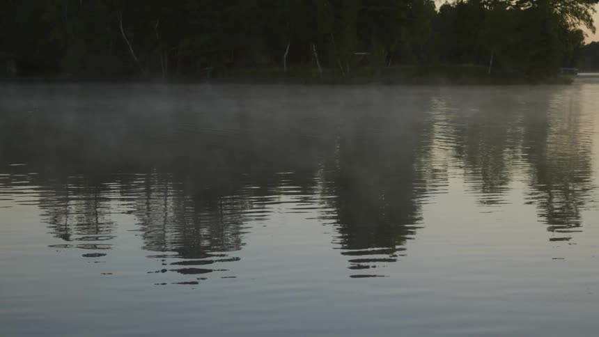 Fog is slowly moving over water at sunset