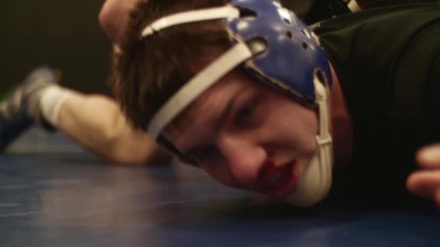 A man young man on a wrestling match struggling with his face on the floor