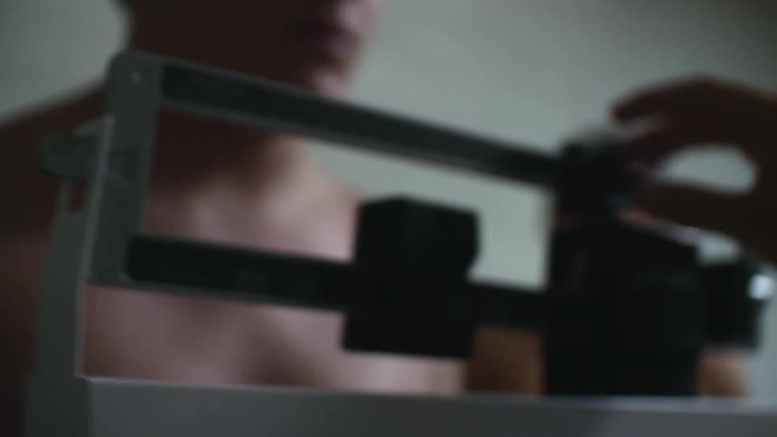 Man stepping on a weight scale and being weighed