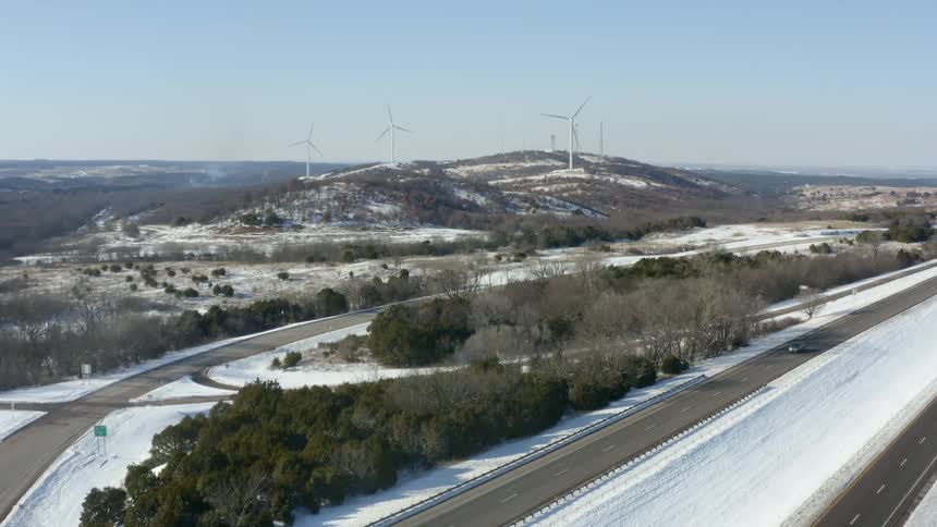 Wind turbines on hills with cars driving past
