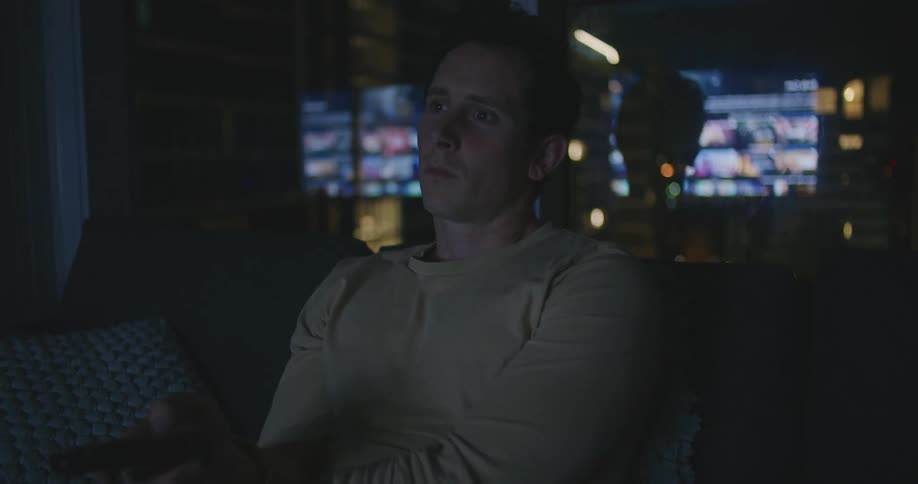 Man sitting in the couch at home watching television at night