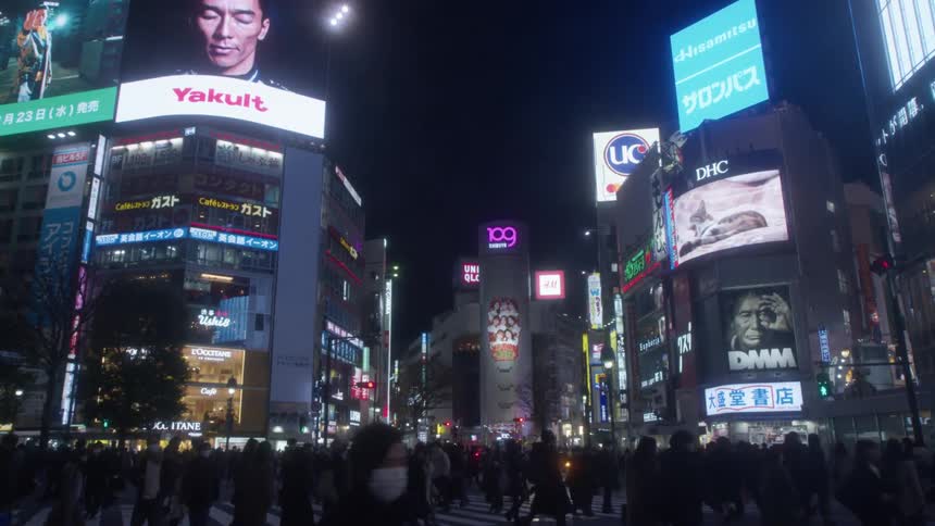 Pedestrians crossing the over the zebra crossing on a busy city intersection at night