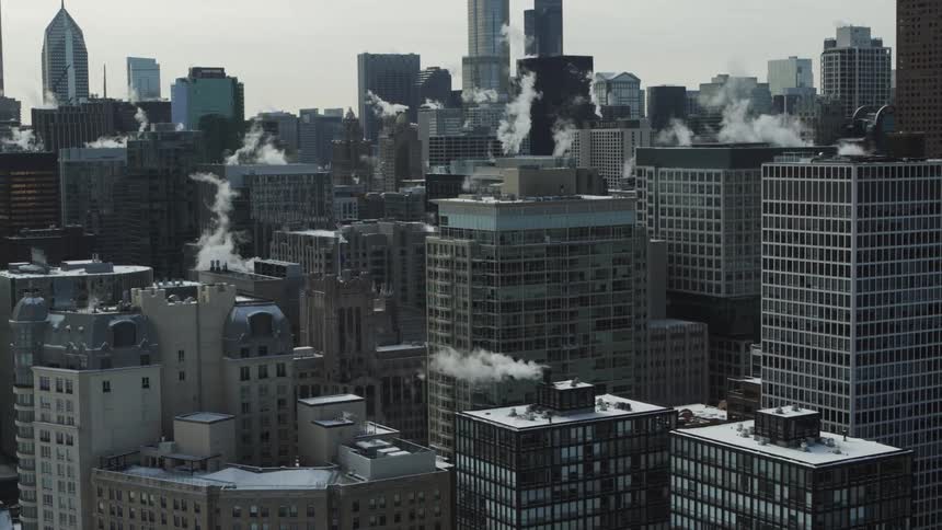 Smoke billows from several rooftop chimneys in Chicago