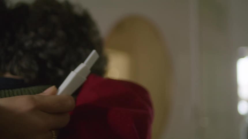A woman holds a pregnancy test while embracing her husband