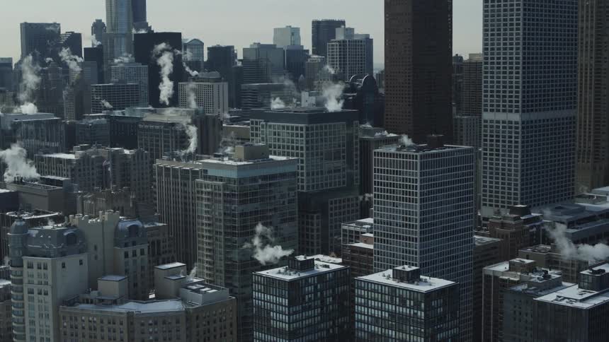 A steady stream of smoke rises from the rooftops of several downtown skyscrapers