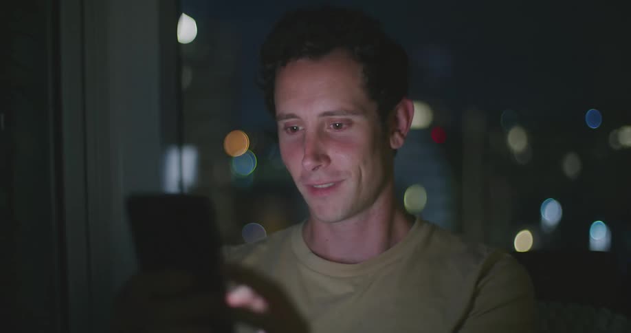 Man scrolling on cell phone indoors at night