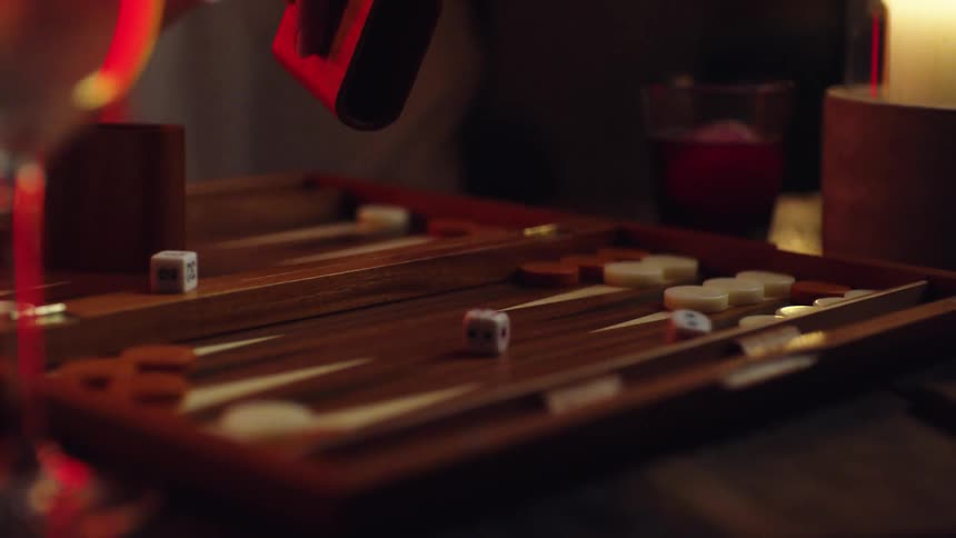 A person at home rolls dice as they play a game