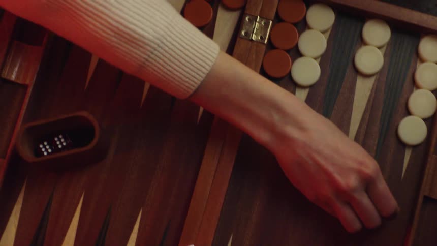 Woman with white sweater plays backgammon