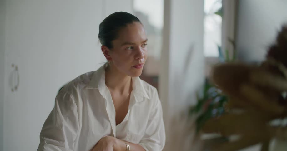 Woman wearing white in white walled room nods while talking