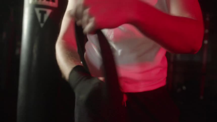 Man wrapping his hands with black bandages inside a gym